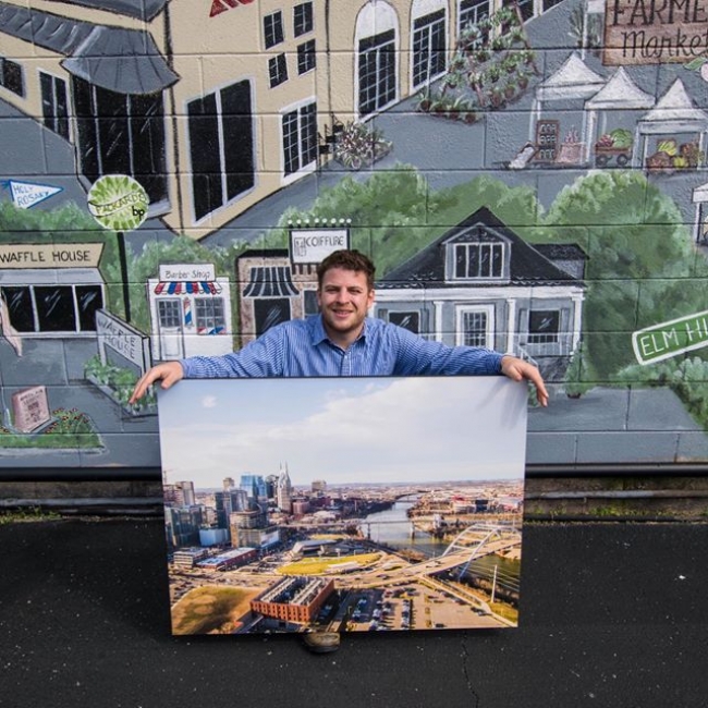 Derek holding one of his images printed on a large canvas